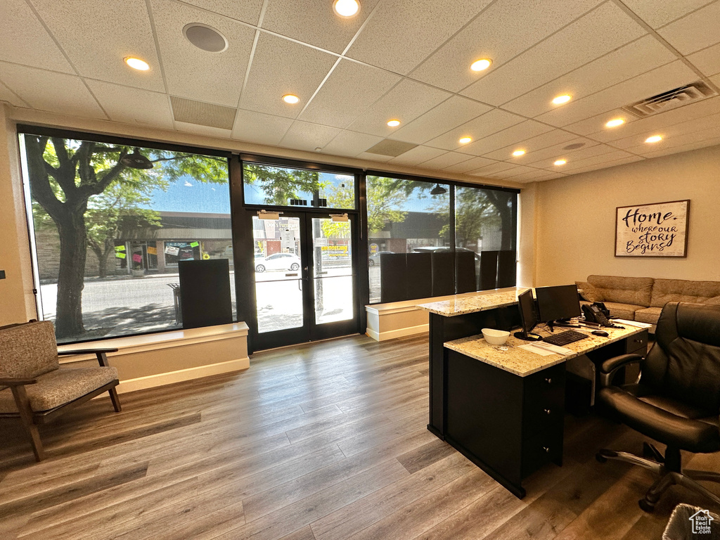 Office space featuring a healthy amount of sunlight, french doors, a paneled ceiling, and hardwood / wood-style floors