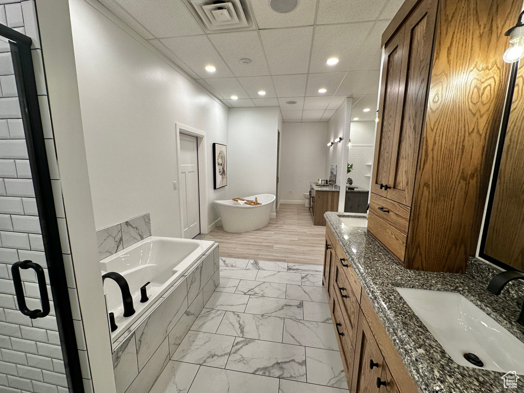 Bathroom featuring tile flooring, a paneled ceiling, shower with separate bathtub, and dual bowl vanity