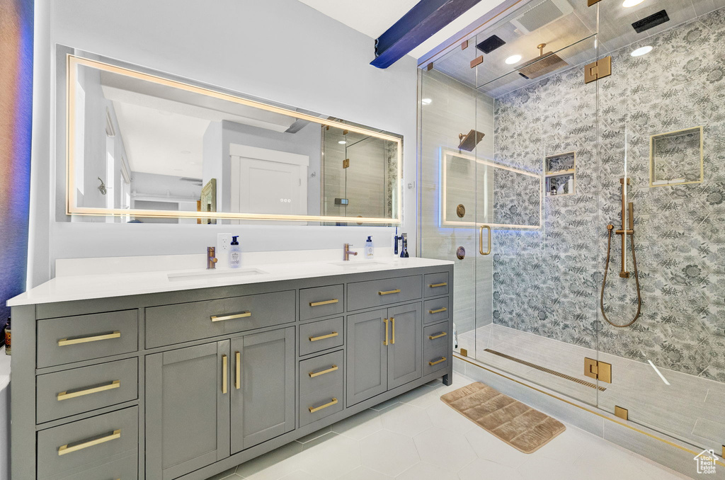 Bathroom featuring a shower with shower door, double sink, oversized vanity, and tile floors