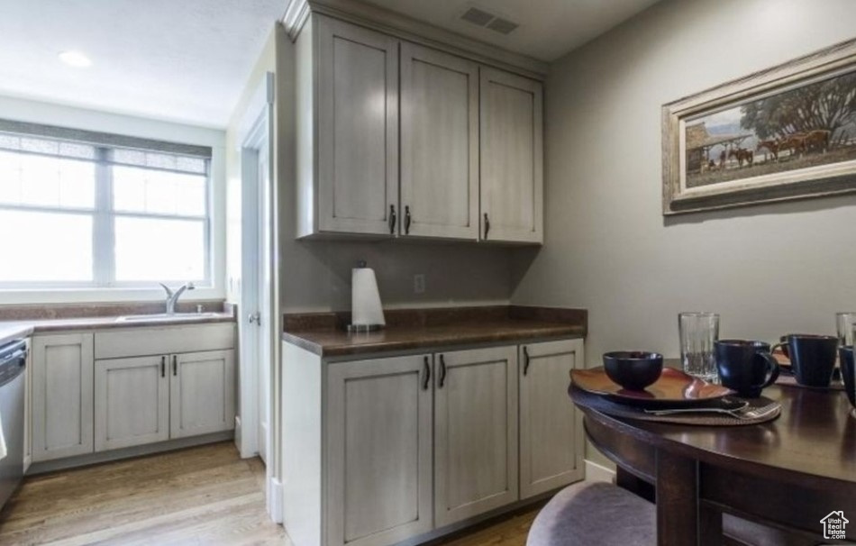 Kitchen featuring dishwasher, sink, light hardwood / wood-style floors, and gray cabinets