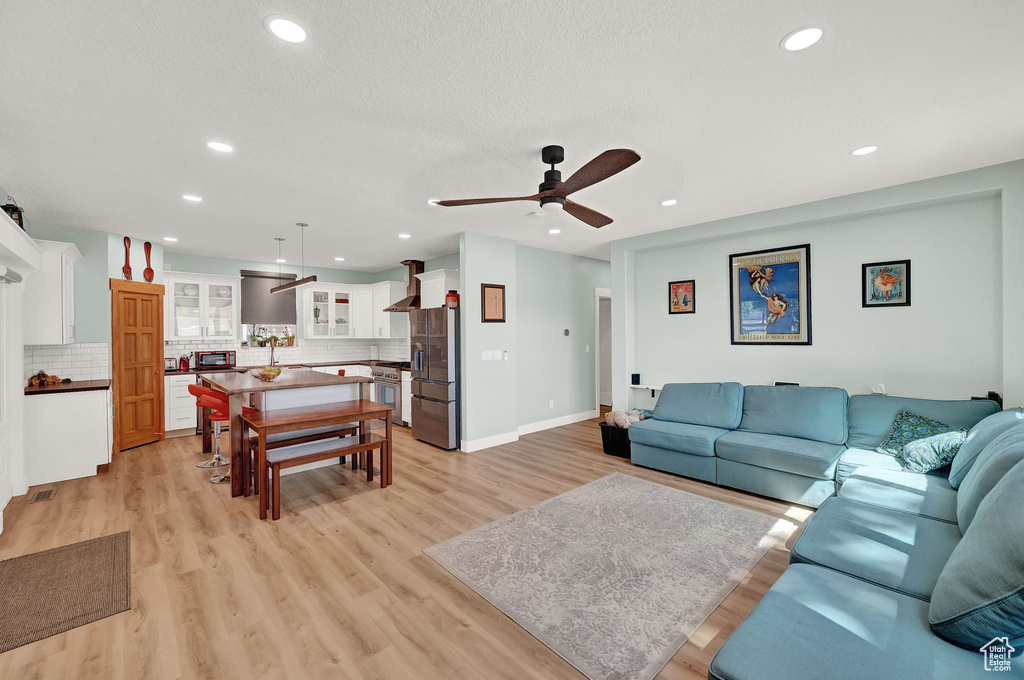 Living room with ceiling fan and light hardwood / wood-style flooring