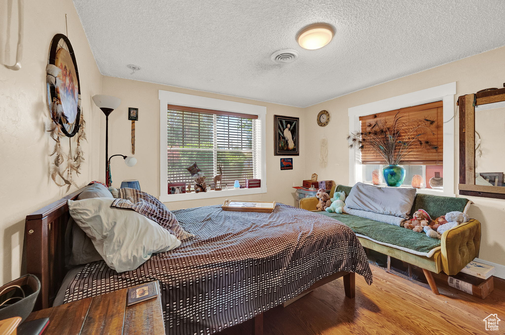 Bedroom with a textured ceiling and wood-type flooring