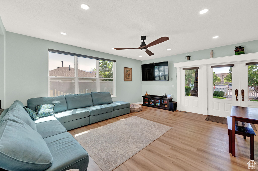 Living room with light hardwood / wood-style floors, french doors, and ceiling fan