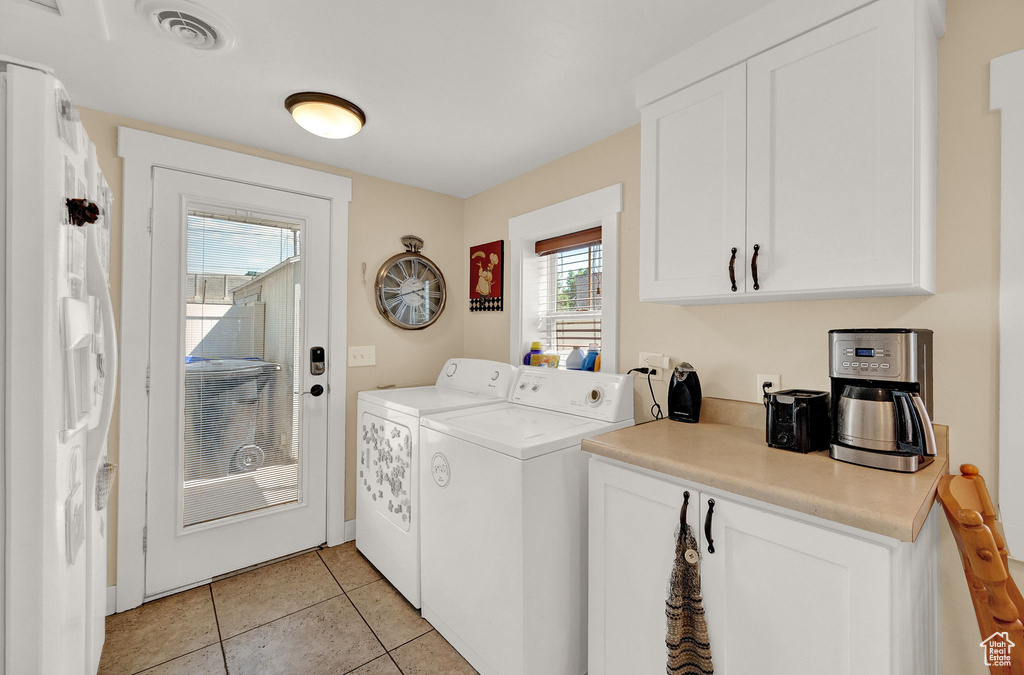 Laundry area with washing machine and dryer, light tile flooring, and cabinets