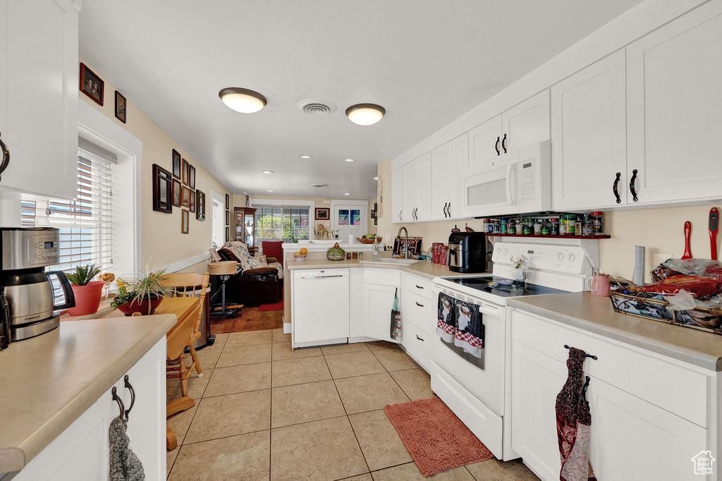 Kitchen with white cabinets, sink, white appliances, and light tile floors