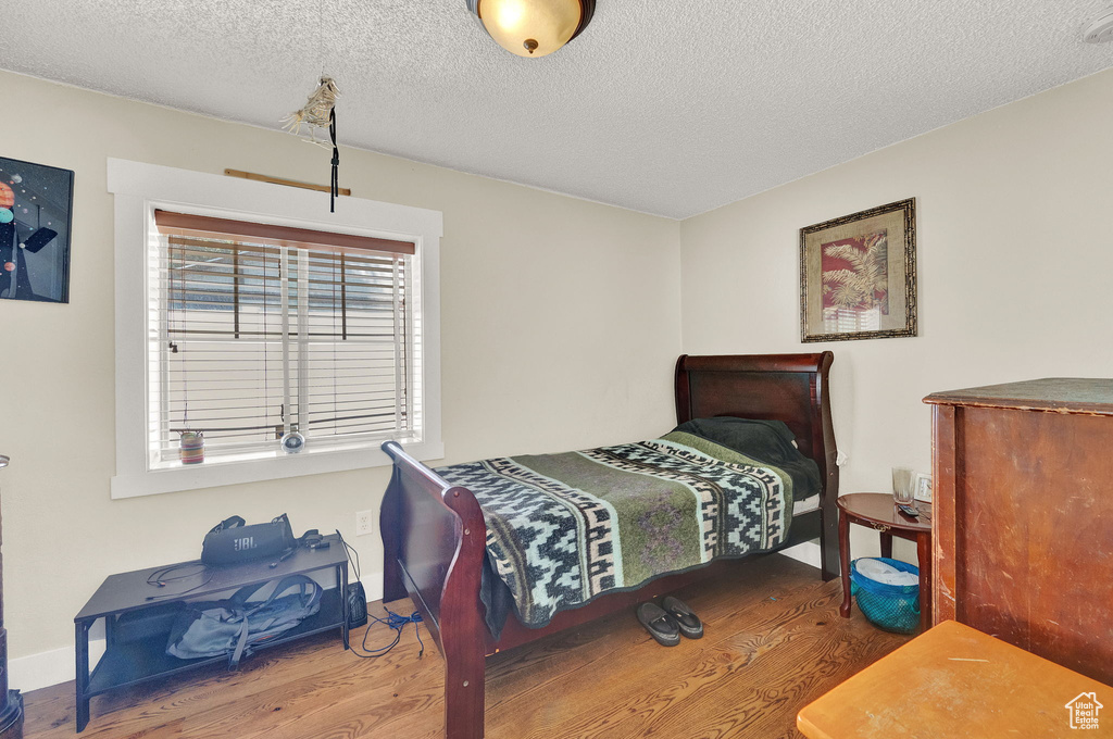 Bedroom featuring hardwood / wood-style floors, a textured ceiling, and multiple windows