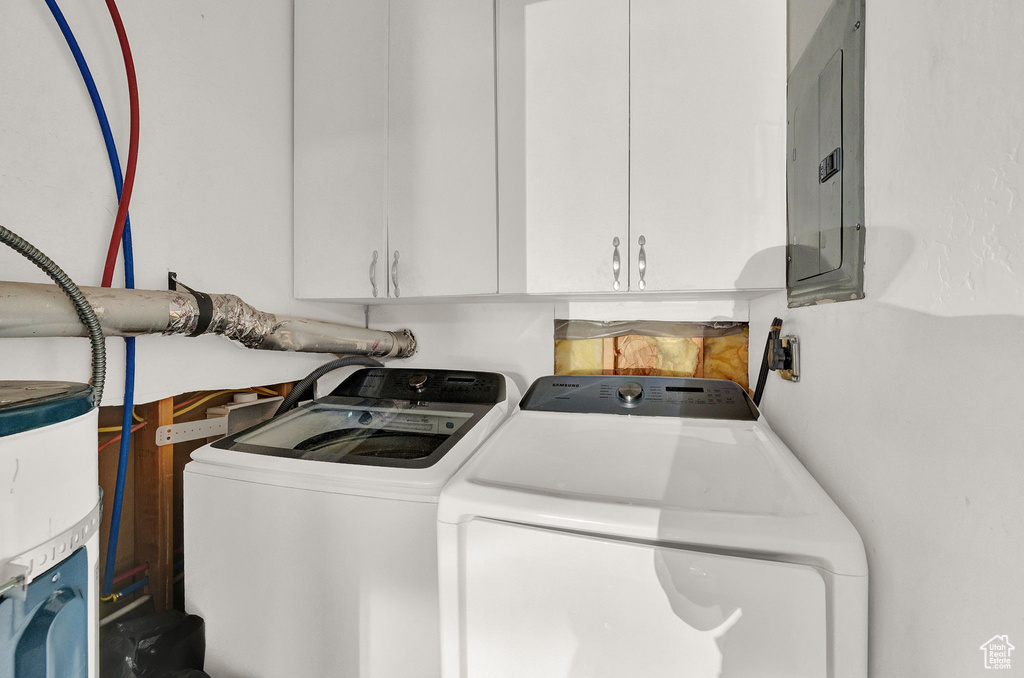 Washroom featuring cabinets, washing machine and clothes dryer, and water heater