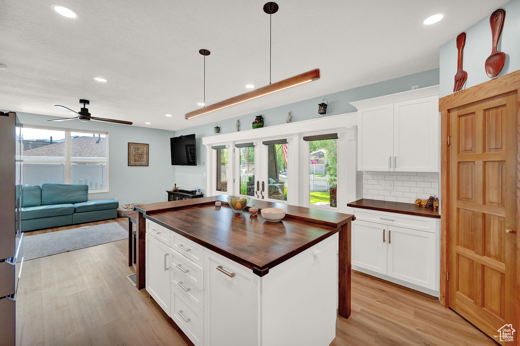 Kitchen featuring decorative light fixtures, light hardwood / wood-style floors, ceiling fan, butcher block counters, and tasteful backsplash