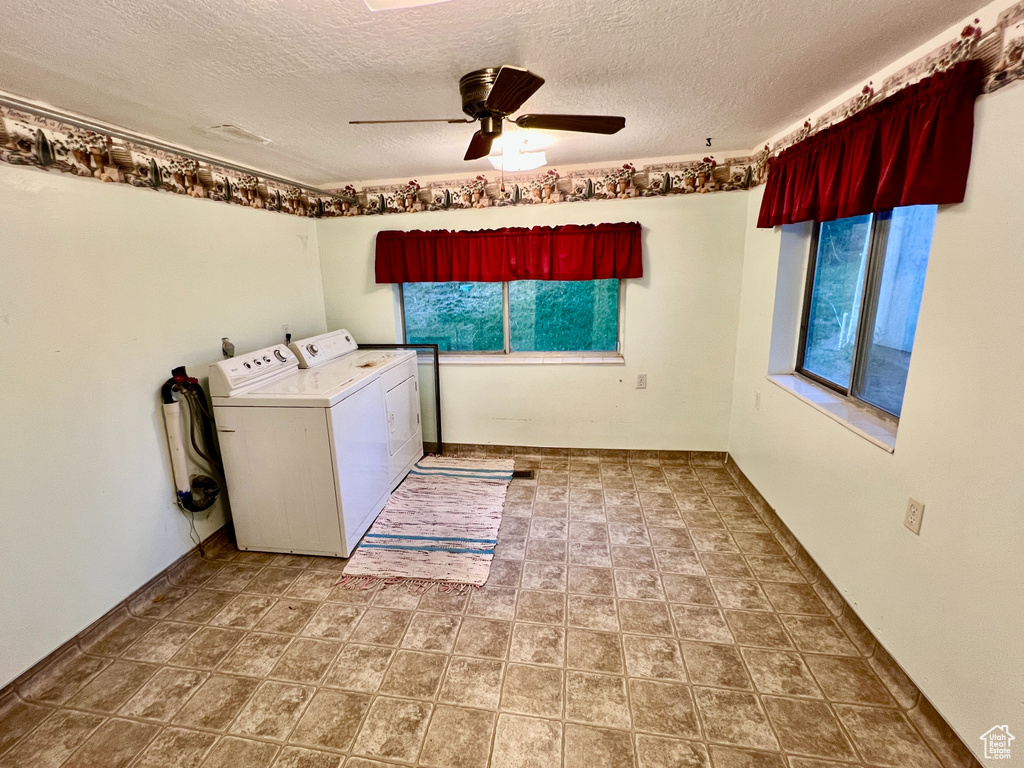 Washroom featuring washing machine and clothes dryer, electric dryer hookup, ceiling fan, tile floors, and a textured ceiling