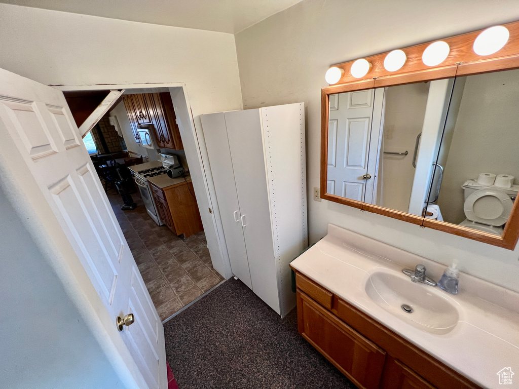 Bathroom with tile floors, washer / dryer, toilet, and vanity with extensive cabinet space