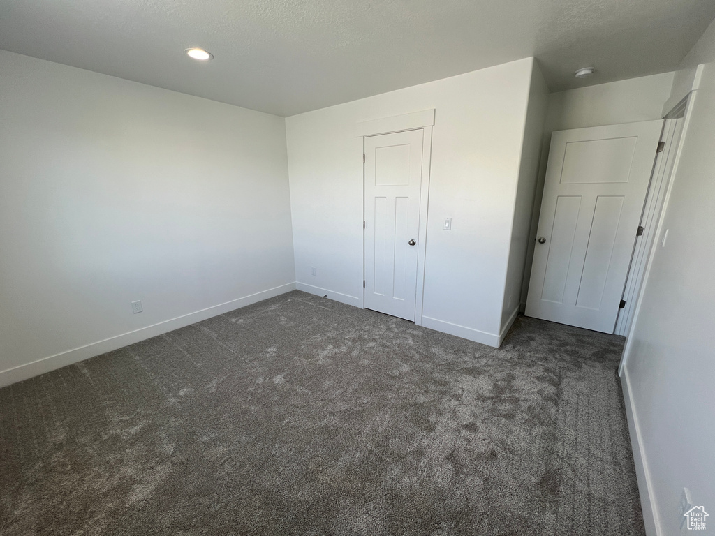 Unfurnished bedroom with a closet and dark carpet