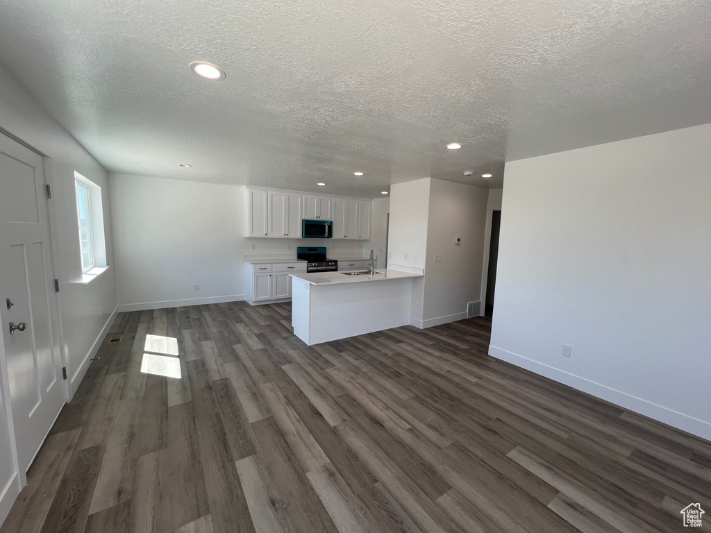 Kitchen with white cabinetry, a textured ceiling, dark hardwood / wood-style floors, kitchen peninsula, and sink