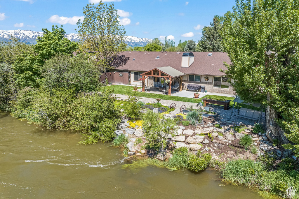 Back of house with a patio area and a deck with water view