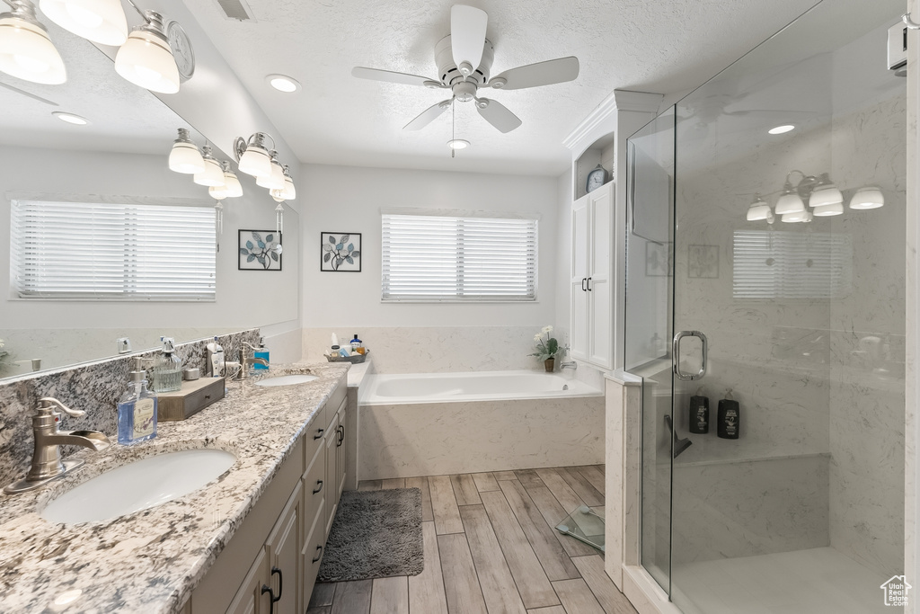 Bathroom featuring ceiling fan, large vanity, independent shower and bath, and double sink