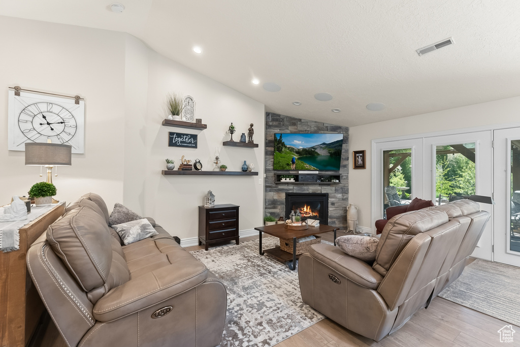 Living room with light hardwood / wood-style floors, a fireplace, and lofted ceiling