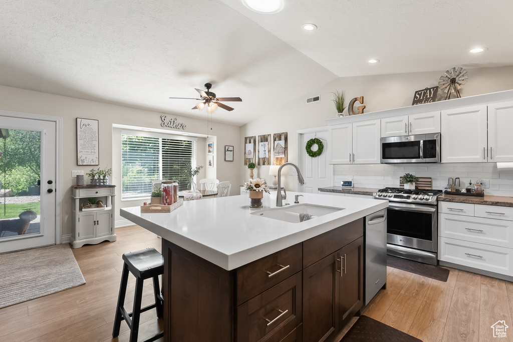 Kitchen featuring ceiling fan, vaulted ceiling, light hardwood / wood-style flooring, and appliances with stainless steel finishes