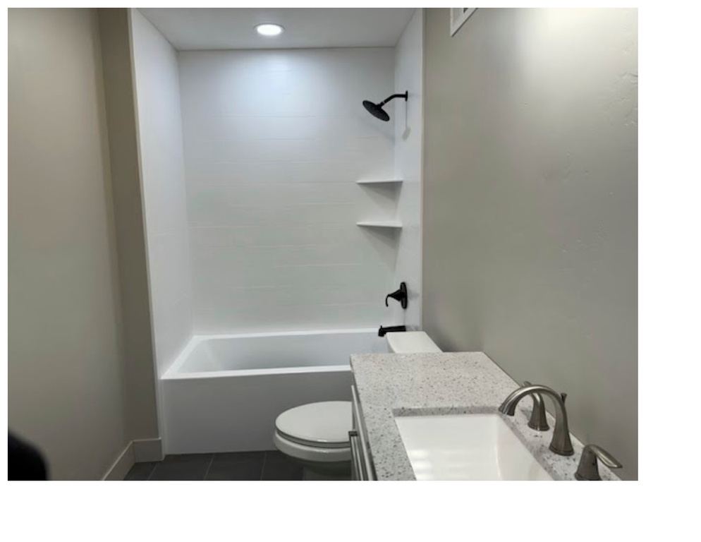 Full bathroom with tiled shower / bath combo, tile patterned flooring, vanity, and toilet