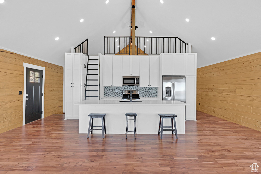 Kitchen with a spacious island, a breakfast bar area, stainless steel appliances, and wooden walls