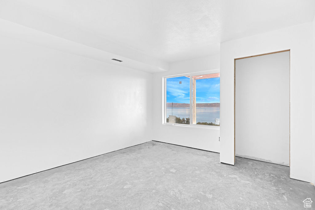 Empty room featuring a water view and concrete flooring