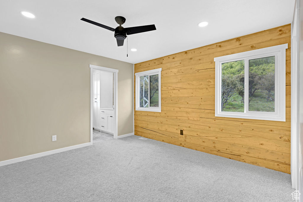 Carpeted empty room with ceiling fan and wood walls