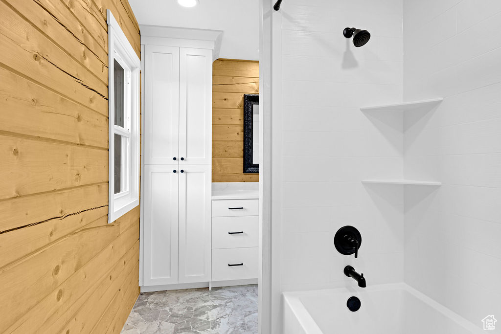 Bathroom with bathtub / shower combination, wooden walls, and tile floors