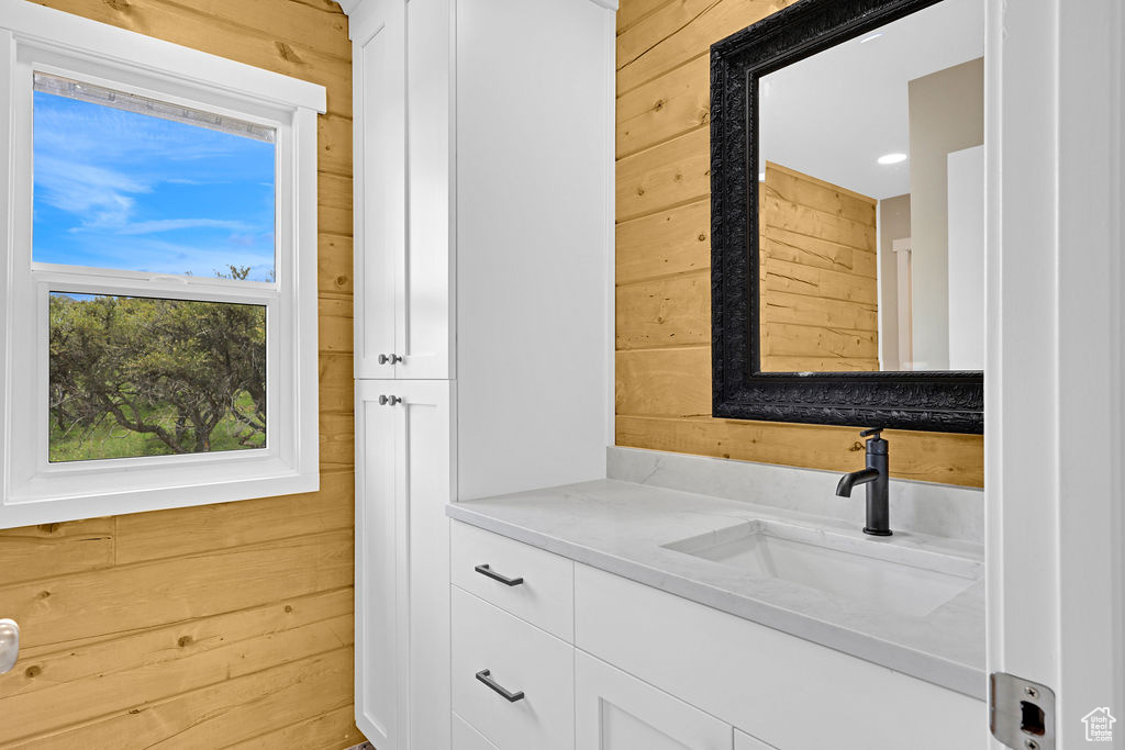 Bathroom featuring wood walls and vanity with extensive cabinet space