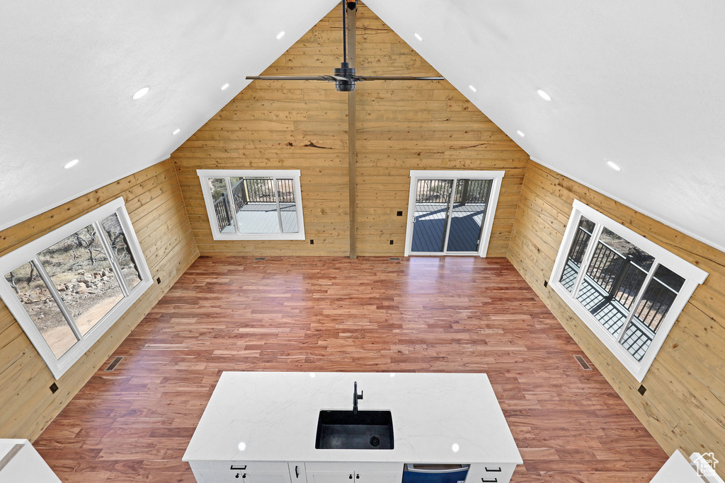 Unfurnished living room featuring wood-type flooring, lofted ceiling, and wood walls