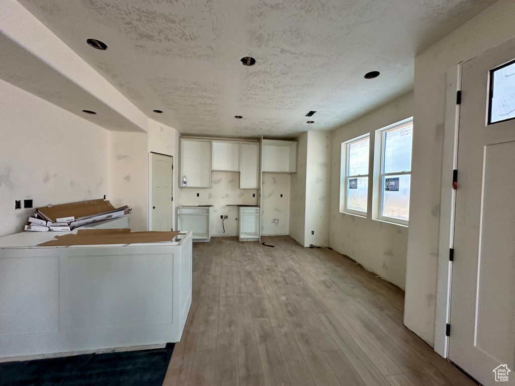 Kitchen with white cabinets, light hardwood / wood-style flooring, and kitchen peninsula