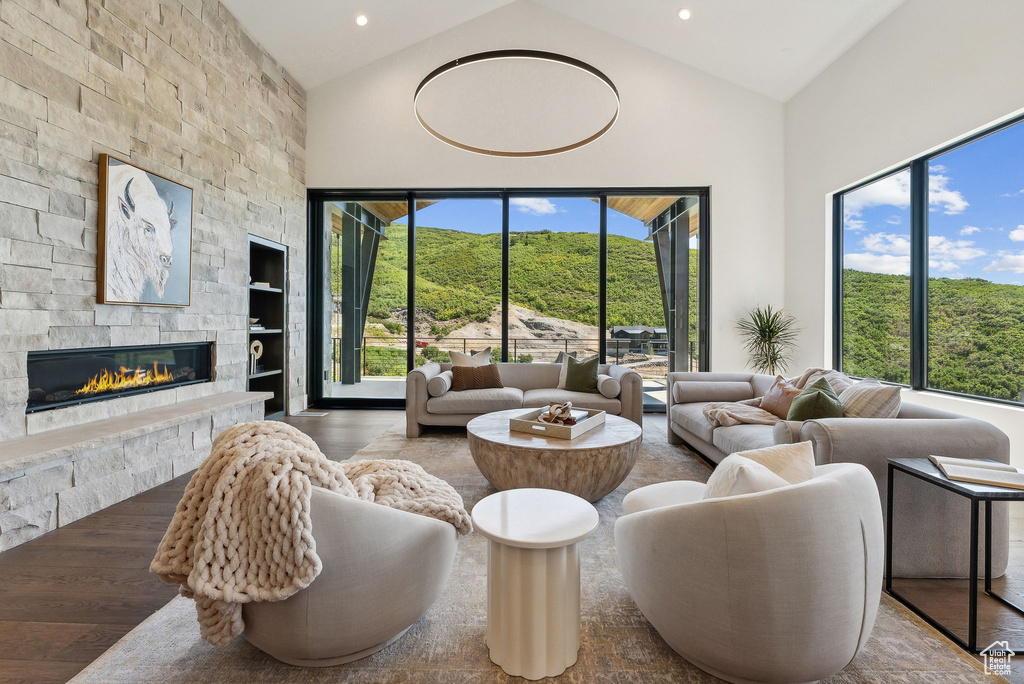 Living room featuring a fireplace, high vaulted ceiling, and hardwood / wood-style floors