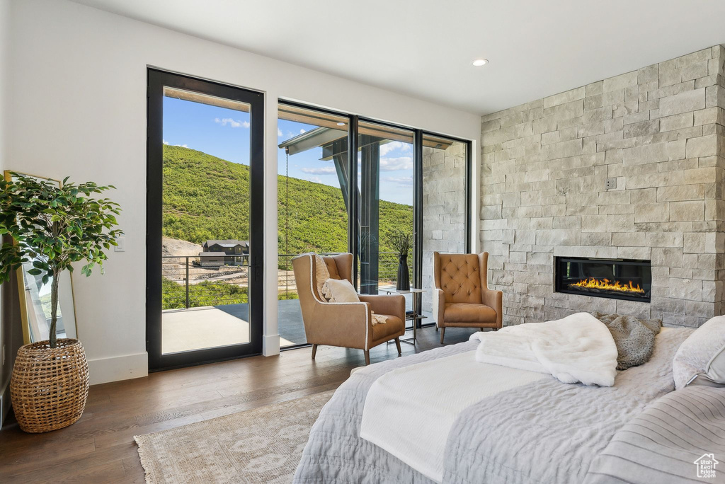 Bedroom featuring a stone fireplace, access to exterior, and dark hardwood / wood-style floors