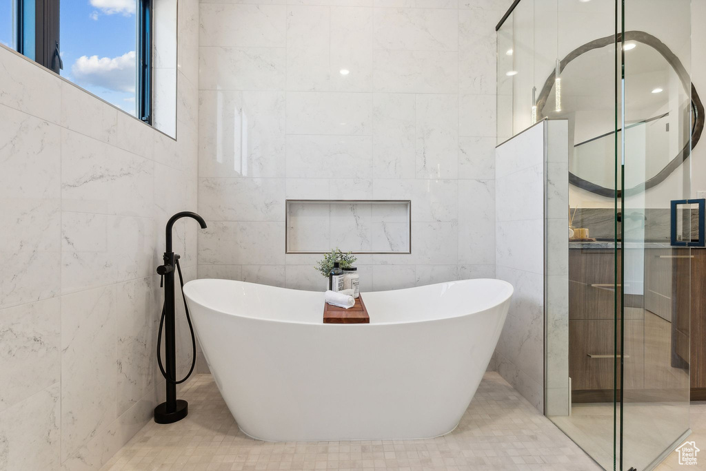 Bathroom featuring tile walls, tile patterned flooring, and a bathing tub