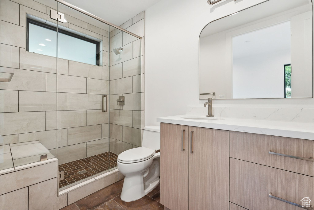 Bathroom featuring a shower with door, vanity, toilet, and tile patterned floors