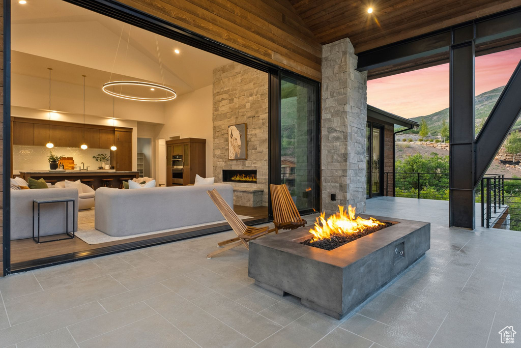 Patio terrace at dusk featuring a fire pit and an outdoor stone fireplace