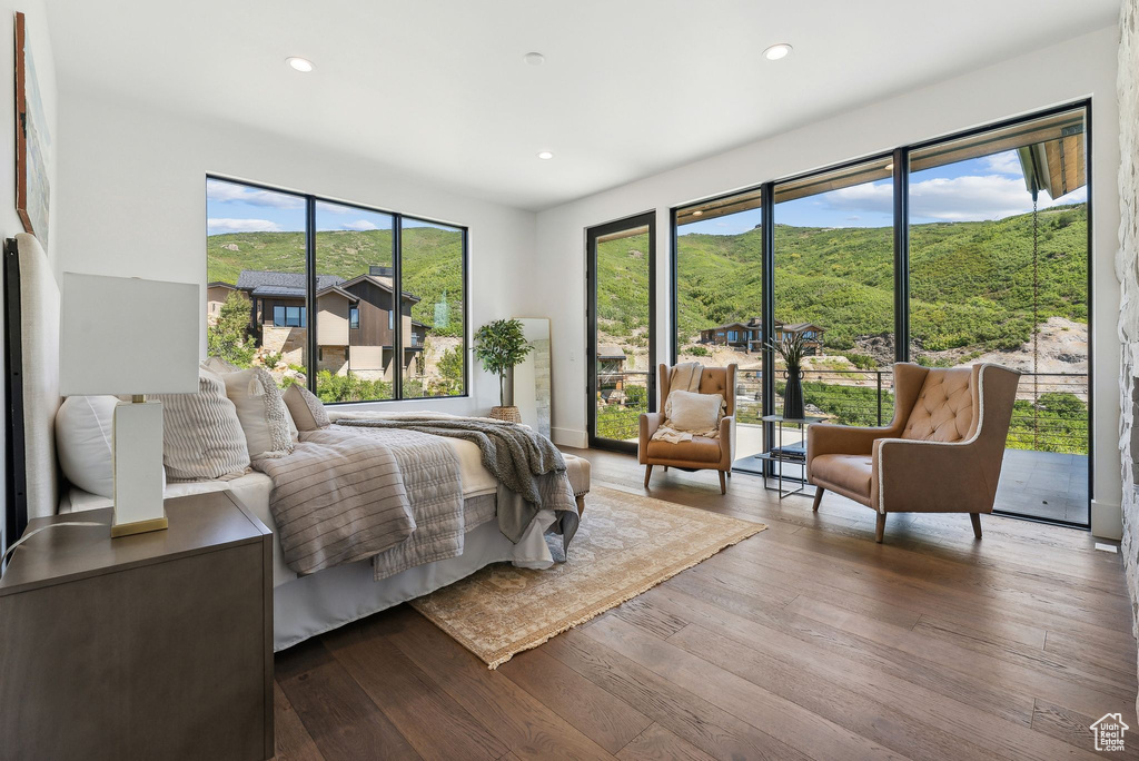 Bedroom featuring multiple windows, a mountain view, dark hardwood / wood-style flooring, and access to outside