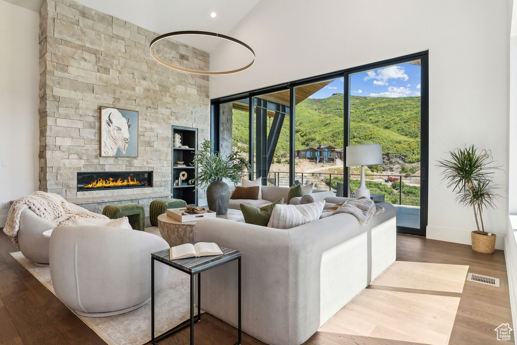 Living room featuring a high ceiling, hardwood / wood-style floors, and a stone fireplace