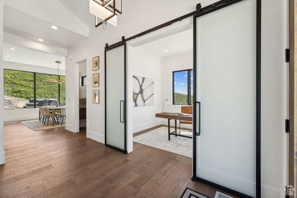 Hallway featuring a barn door, lofted ceiling, plenty of natural light, and dark hardwood / wood-style floors