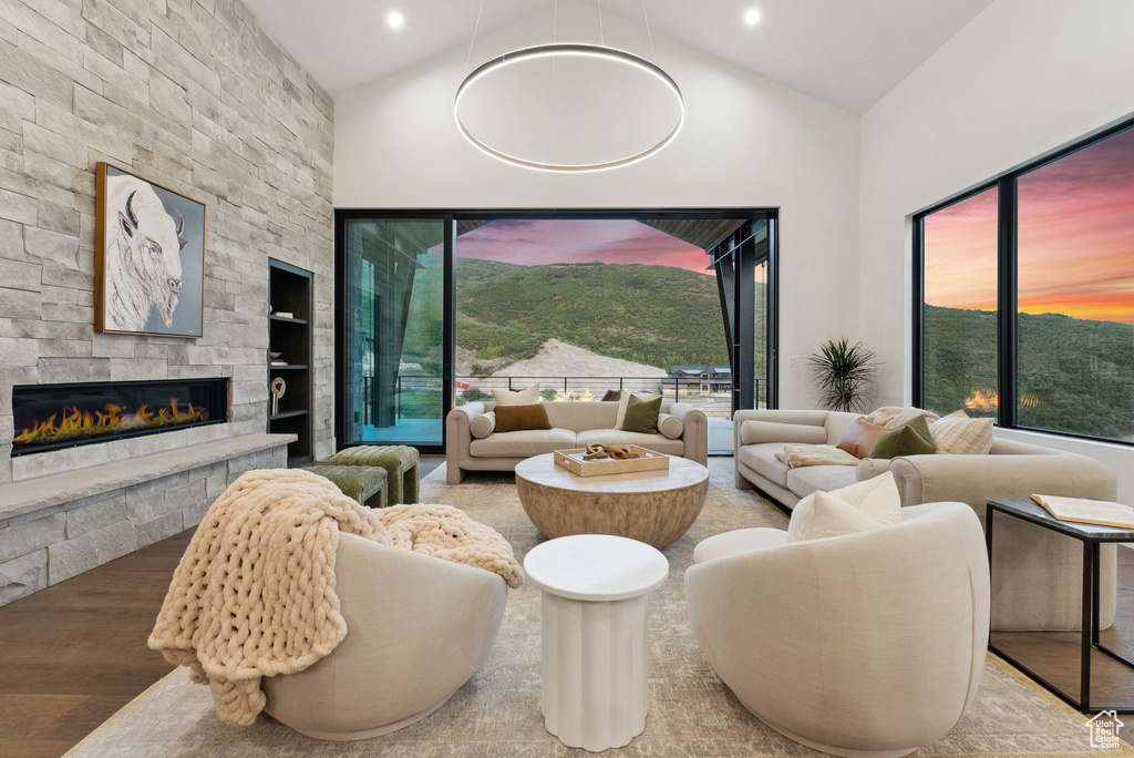 Living room featuring a fireplace, built in features, high vaulted ceiling, and hardwood / wood-style floors