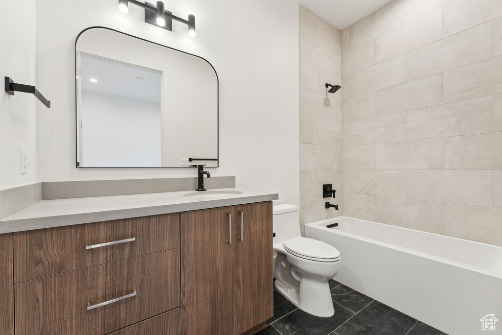 Full bathroom with tile patterned flooring, toilet, tiled shower / bath combo, and vanity