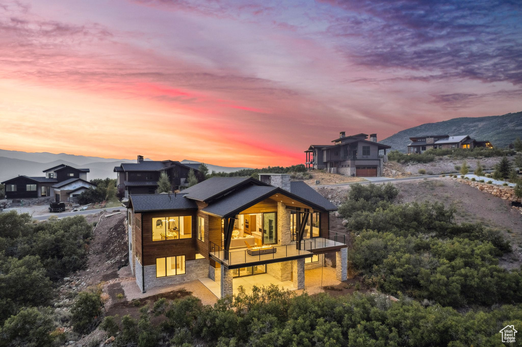 Back house at dusk featuring a balcony and a mountain view