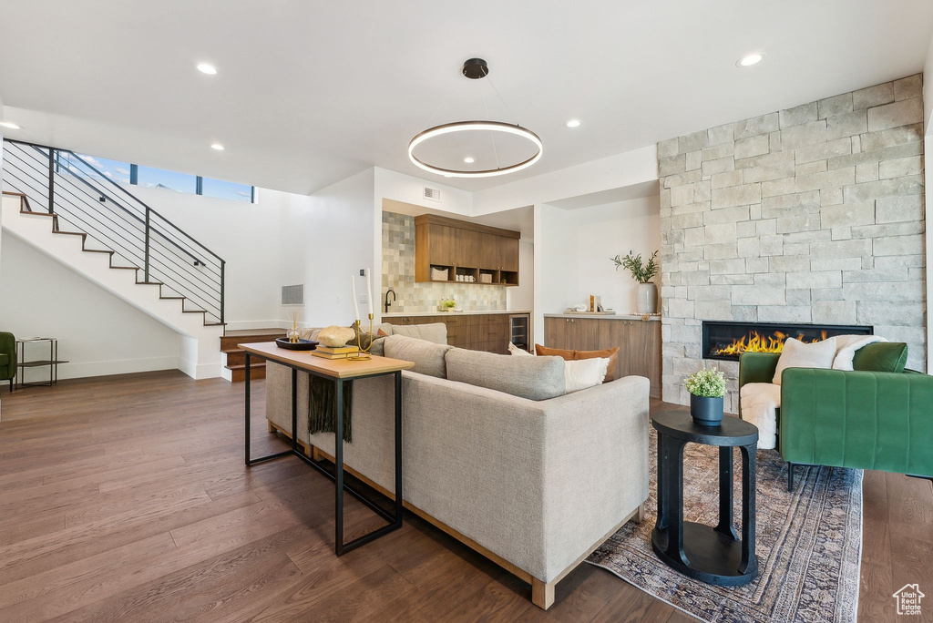 Living room featuring dark hardwood / wood-style floors, a chandelier, and a stone fireplace