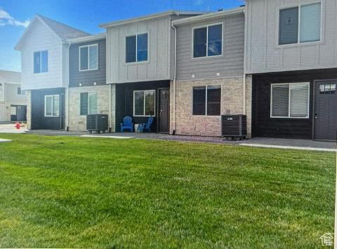 Back of house featuring central AC, a lawn, and a patio