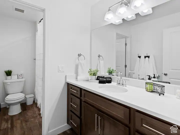 Bathroom with wood-type flooring, toilet, and vanity