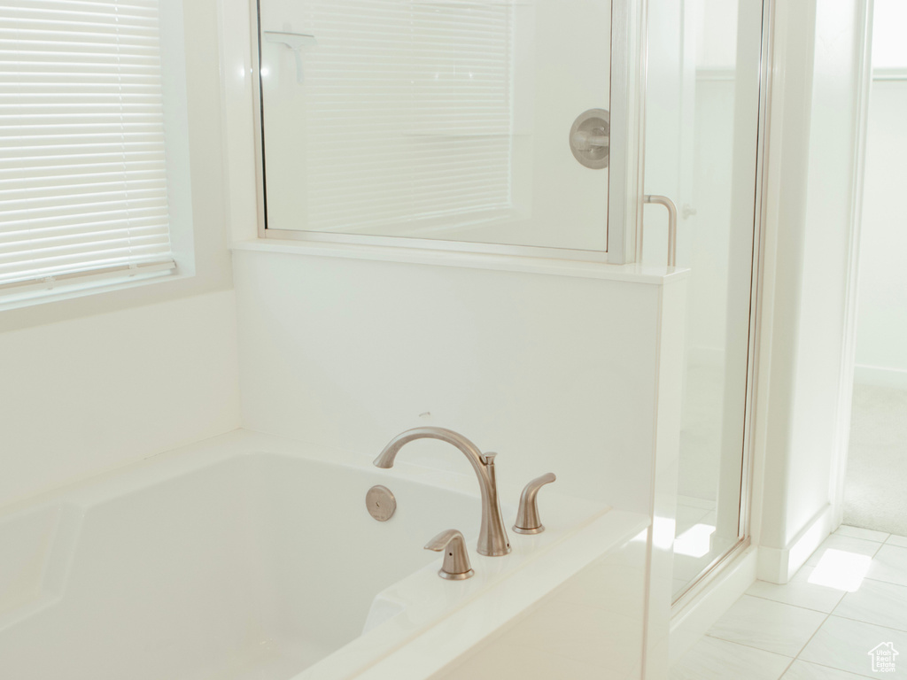 Bathroom featuring tile flooring and shower with separate bathtub