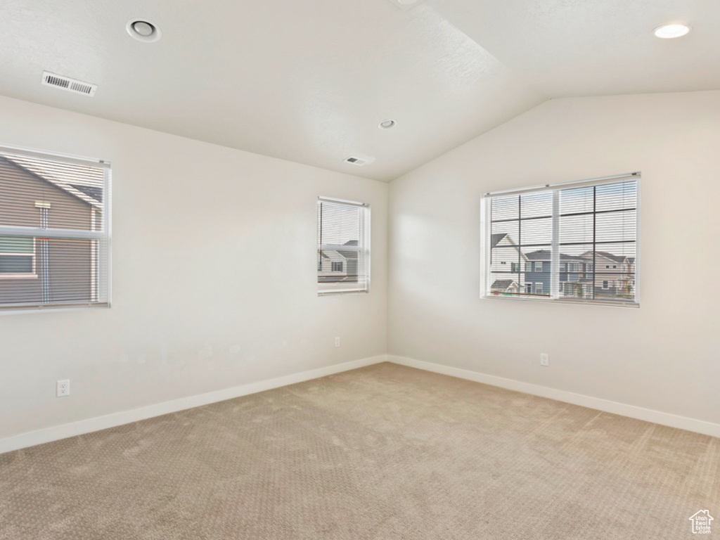 Carpeted empty room featuring lofted ceiling