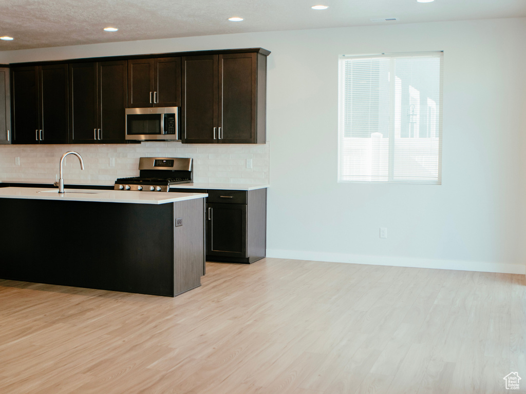 Kitchen featuring appliances with stainless steel finishes, sink, light hardwood / wood-style floors, and tasteful backsplash