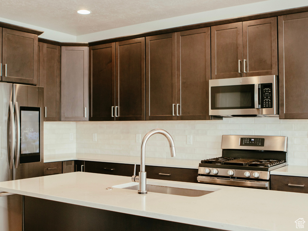 Kitchen featuring sink, tasteful backsplash, dark brown cabinets, and stainless steel appliances