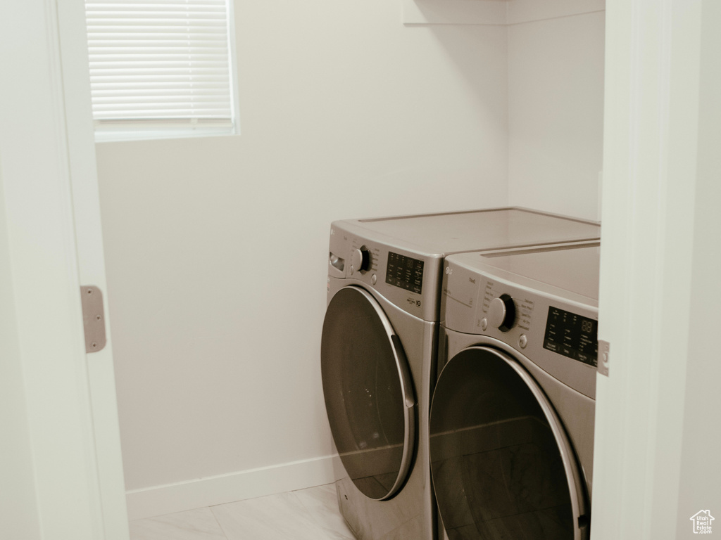 Laundry room featuring washer and dryer and light tile flooring