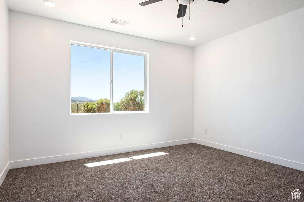 Carpeted empty room featuring ceiling fan