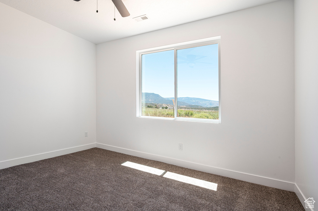 Carpeted empty room featuring a mountain view and ceiling fan