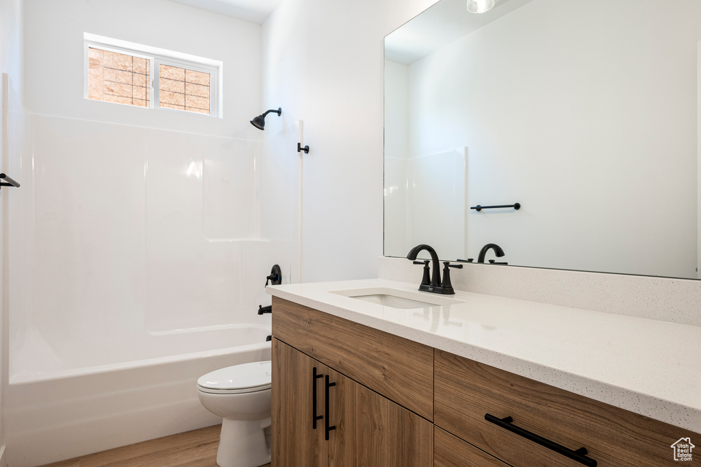 Full bathroom featuring hardwood / wood-style floors, shower / bath combination, toilet, and vanity